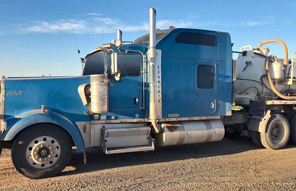 Sand Man Trucking truck 103, a blue Kenworth W900 pulling a vacuum trailer