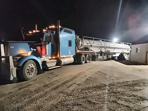 Sand Man Trucking Kenworth with a tank trailer on location at night